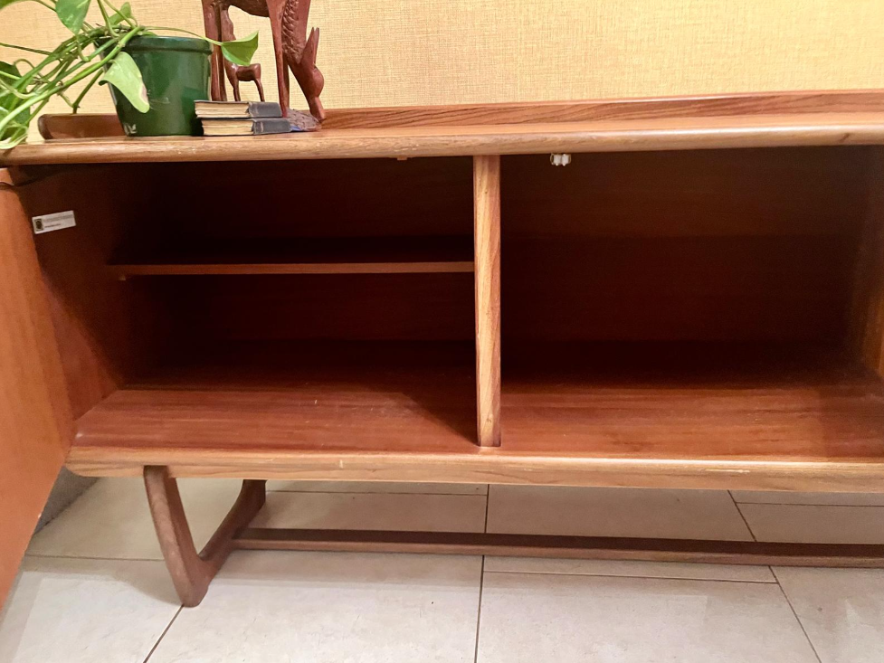 Mid-century modern wooden sideboard with a warm honey finish, featuring three cabinet doors on the left and three drawers on the right, with matching wood handles and angled legs.