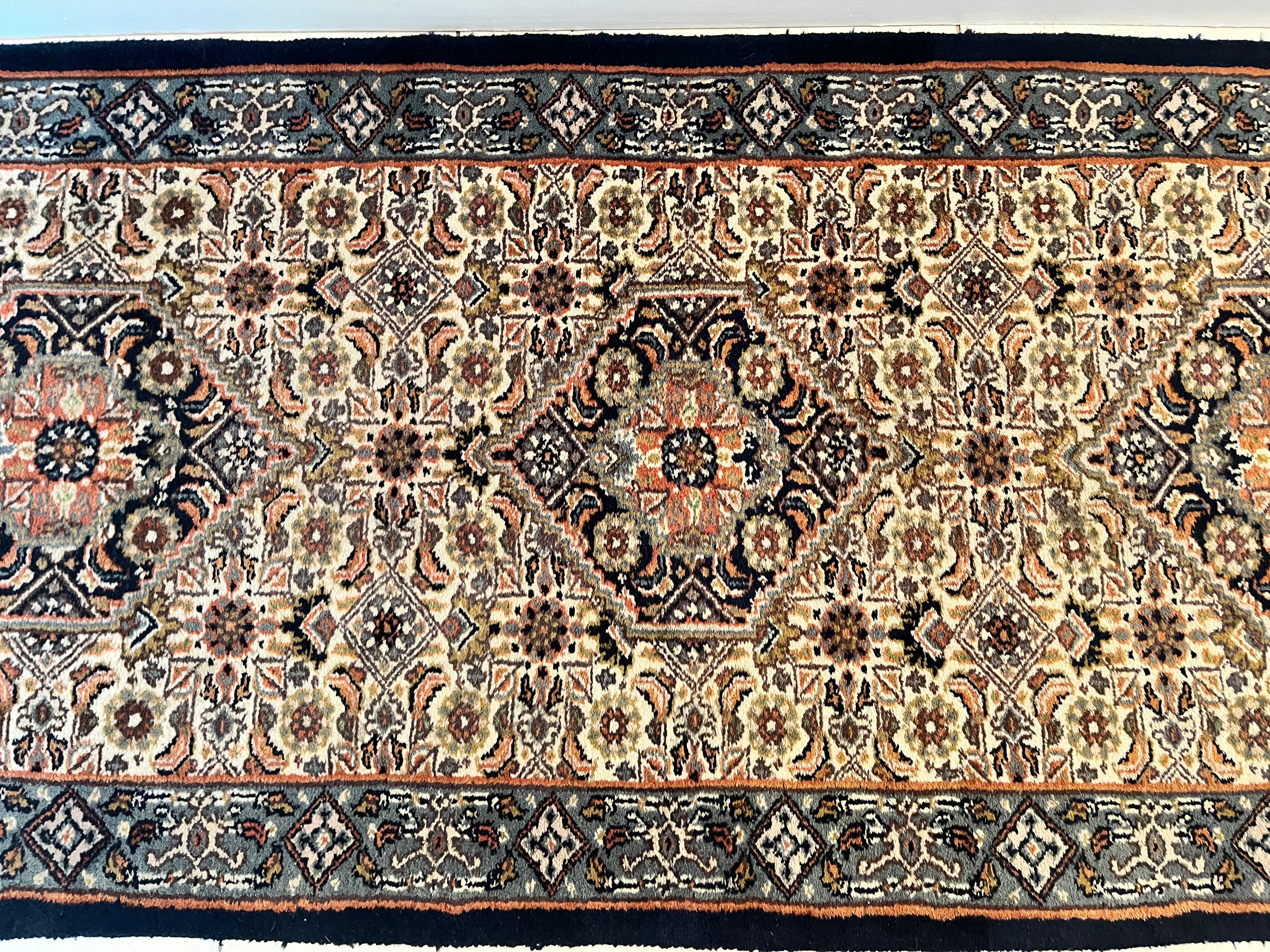 A long traditional vintage runner rug with beige and black fringe, displayed on a light tiled hallway floor y Grace & Joy Furniture