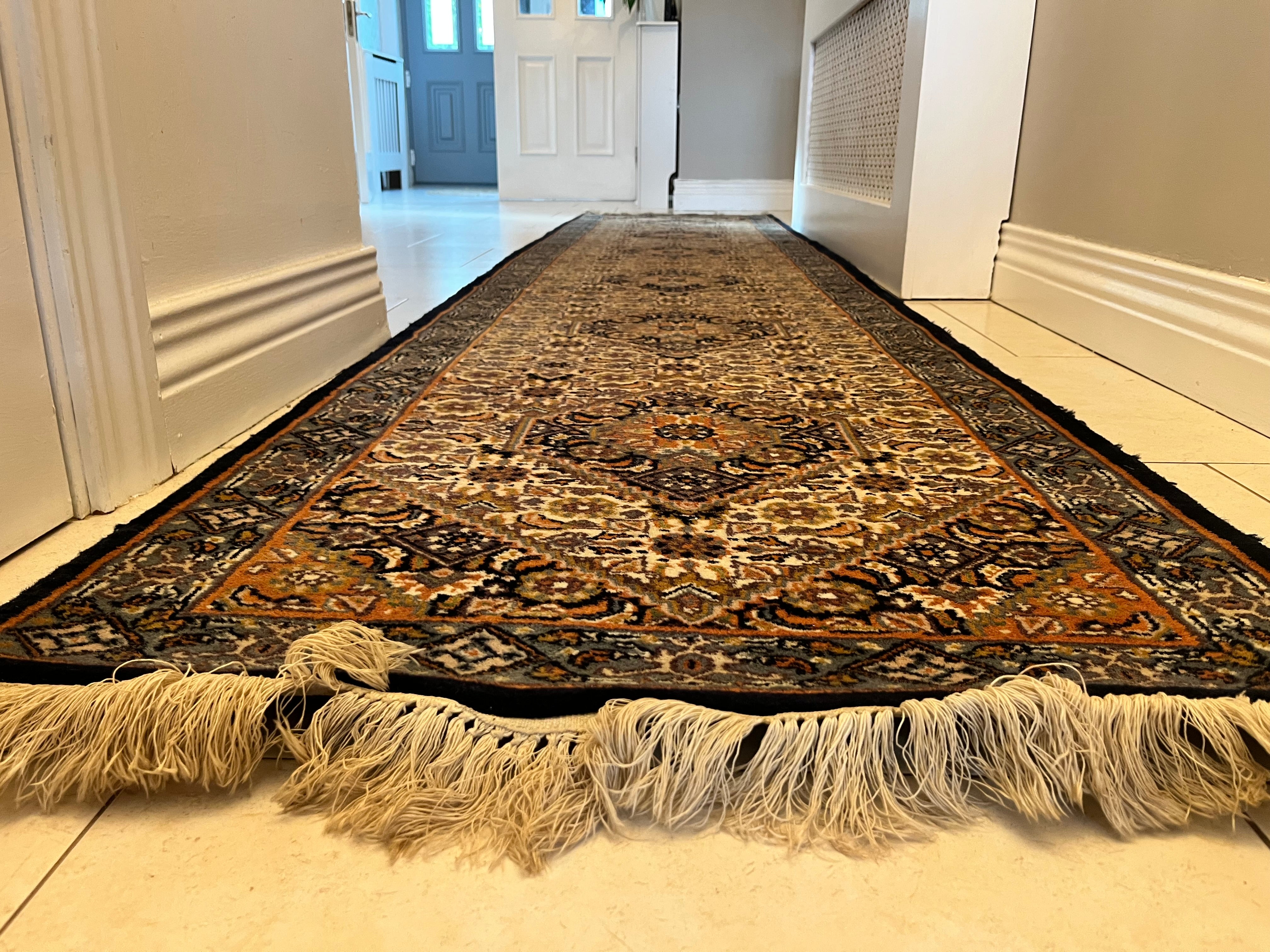 A long traditional vintage runner rug with beige and black fringe, displayed on a light tiled hallway floor y Grace & Joy Furniture
