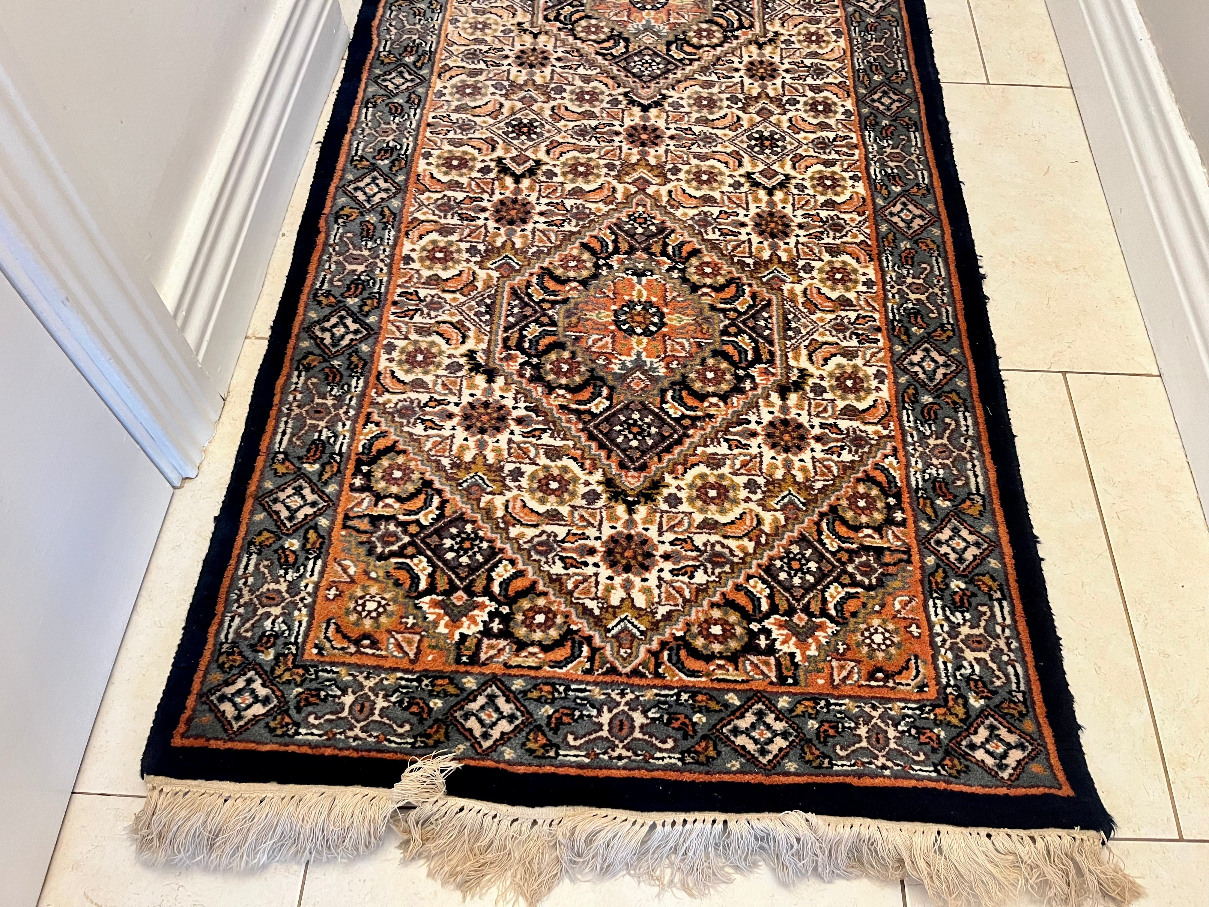 A long traditional vintage runner rug with beige and black fringe, displayed on a light tiled hallway floor y Grace & Joy Furniture