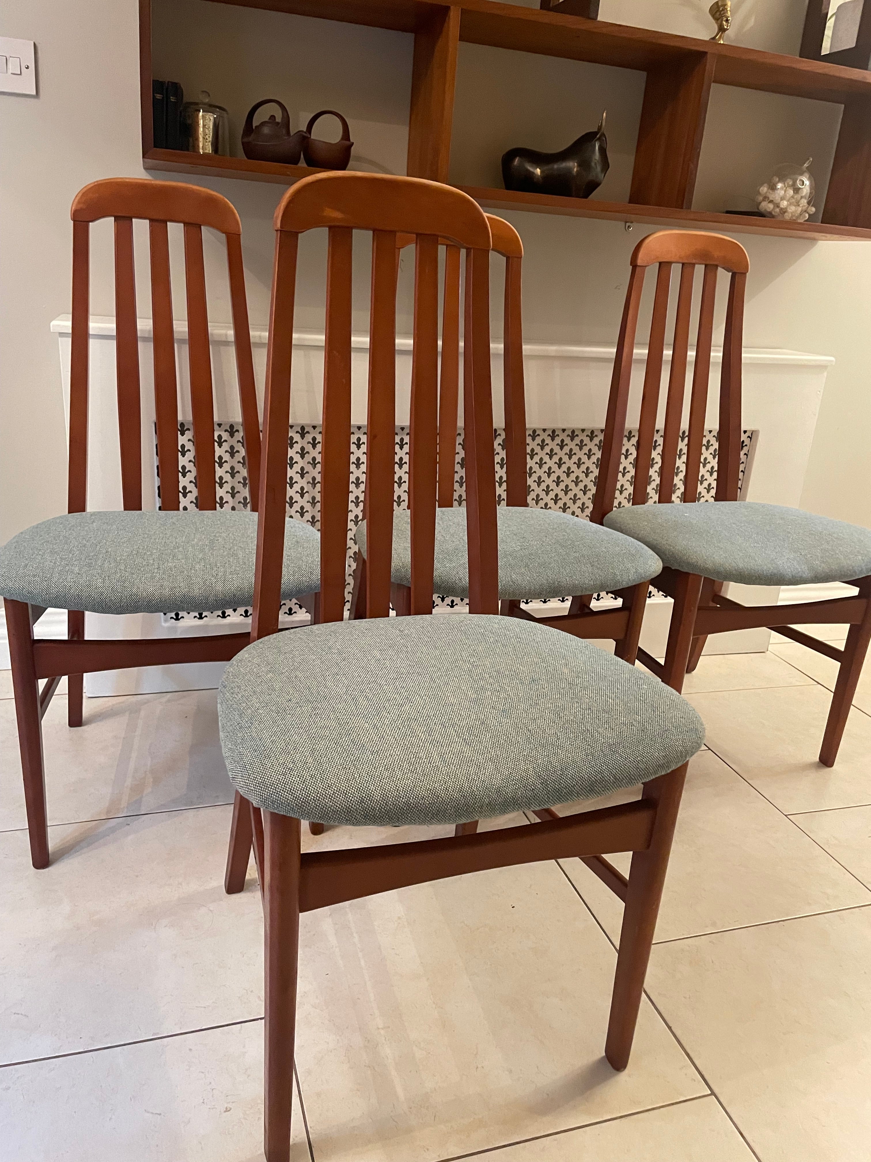 A wooden mid century Jenitique dining chair with a tall slatted backrest and a light blue upholstered seat cushion, shown on a gray wood floor against a white wall by Grace & Joy Furniture