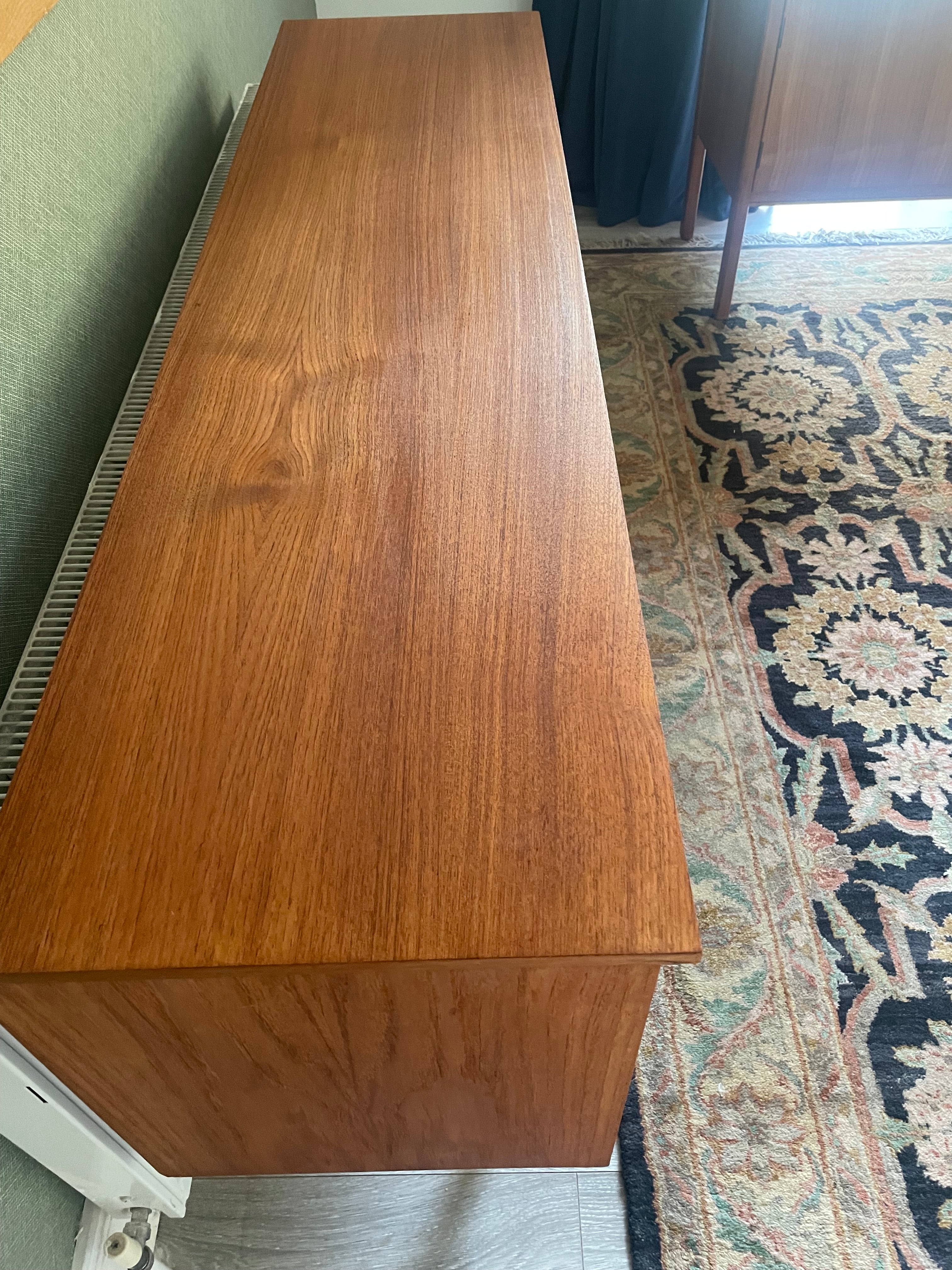Restored mid-century modern wooden credenza or cabinet with three curved doors and circular pull handles, photographed in a home interior with wood flooring and a patterned rug visible by Grace & Joy Furniture