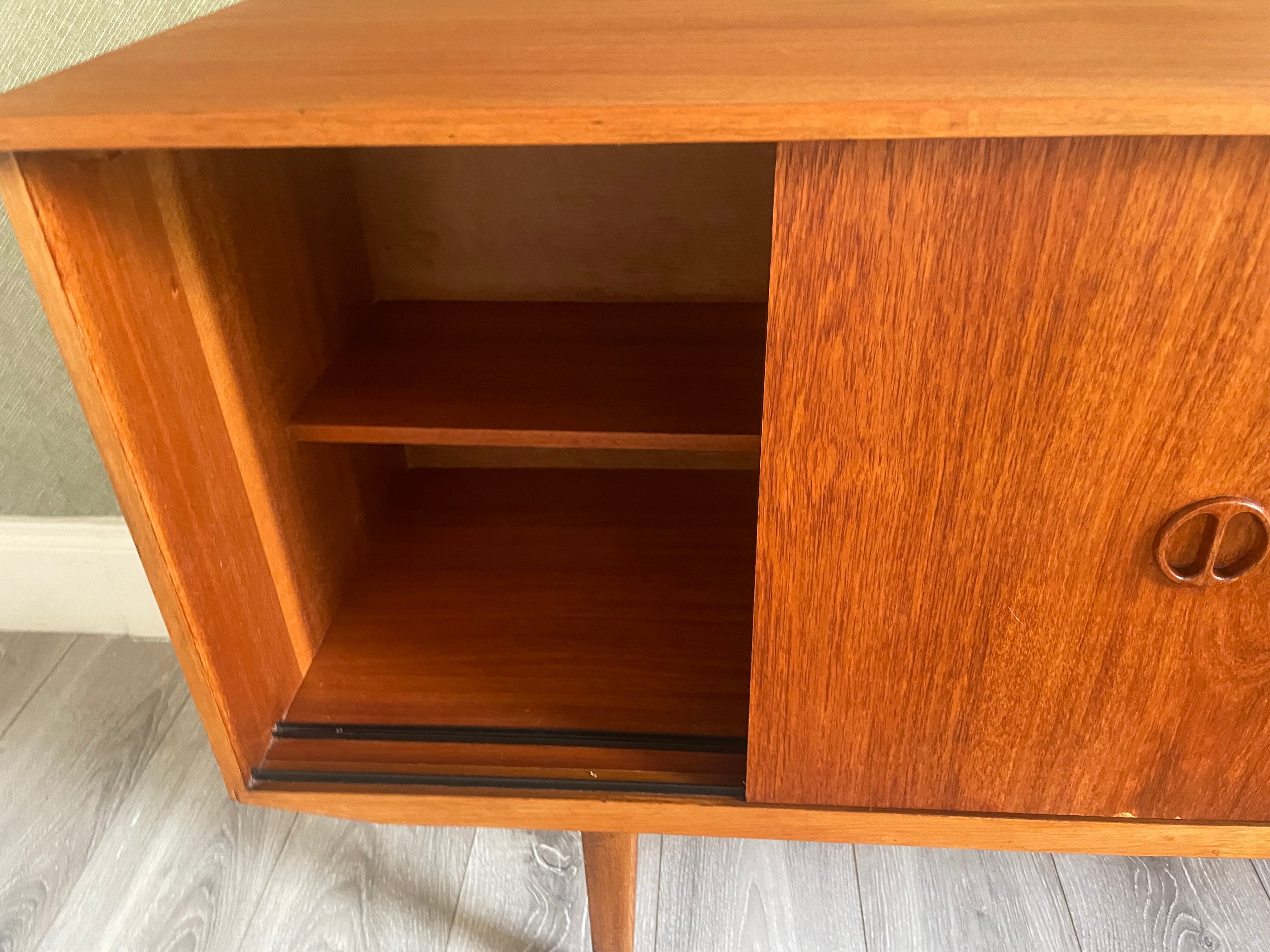 Restored mid-century modern wooden credenza or cabinet with three curved doors and circular pull handles, photographed in a home interior with wood flooring and a patterned rug visible by Grace & Joy Furniture