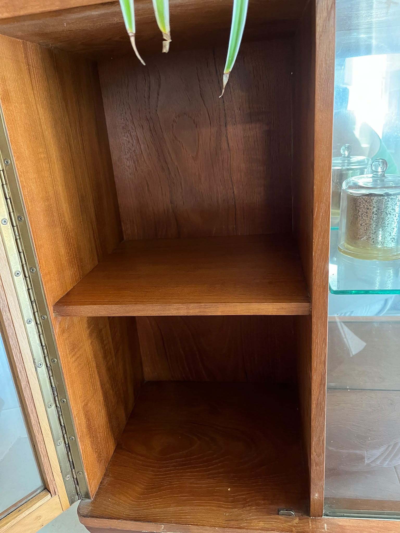 A mid-century modern SF Quinn wooden display cabinet with glass doors, shown in a home interior setting with tiled floors and textured walls by Grace & Joy Furniture