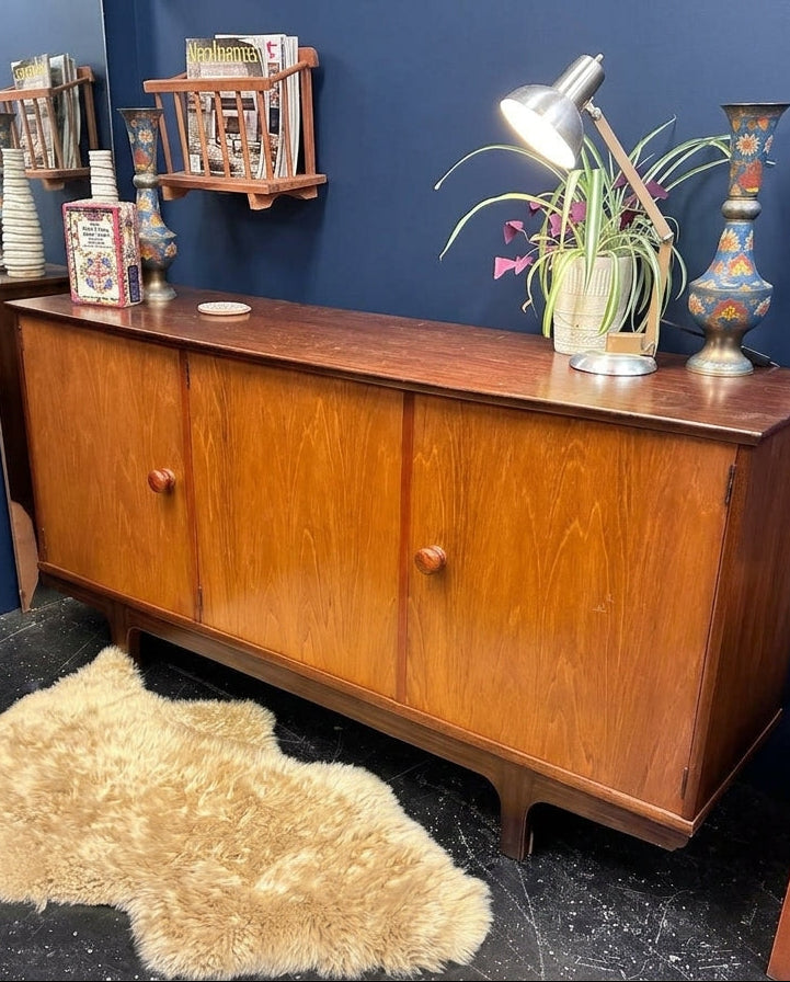 beautiful danish teak sideboard against a navy wall.