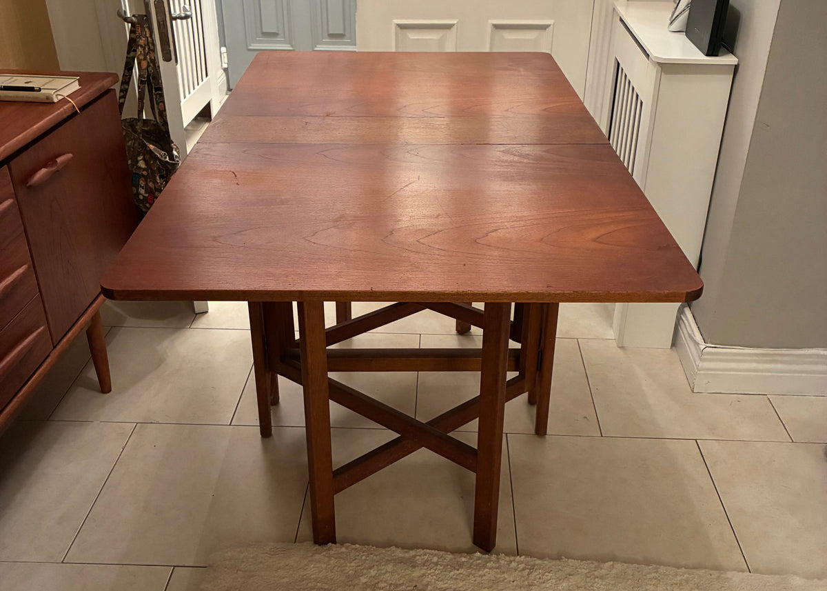 A dark brown wooden dining table with matching wooden stools, shown in a home interior setting with tiled floors and a textured wall.