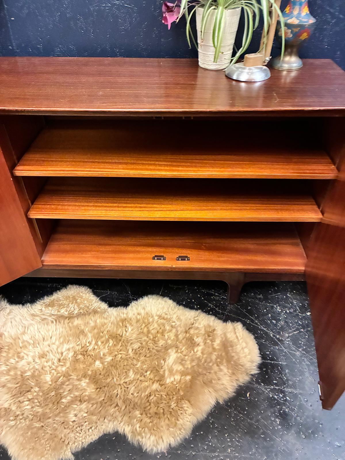 beautiful danish teak sideboard against a navy wall.
