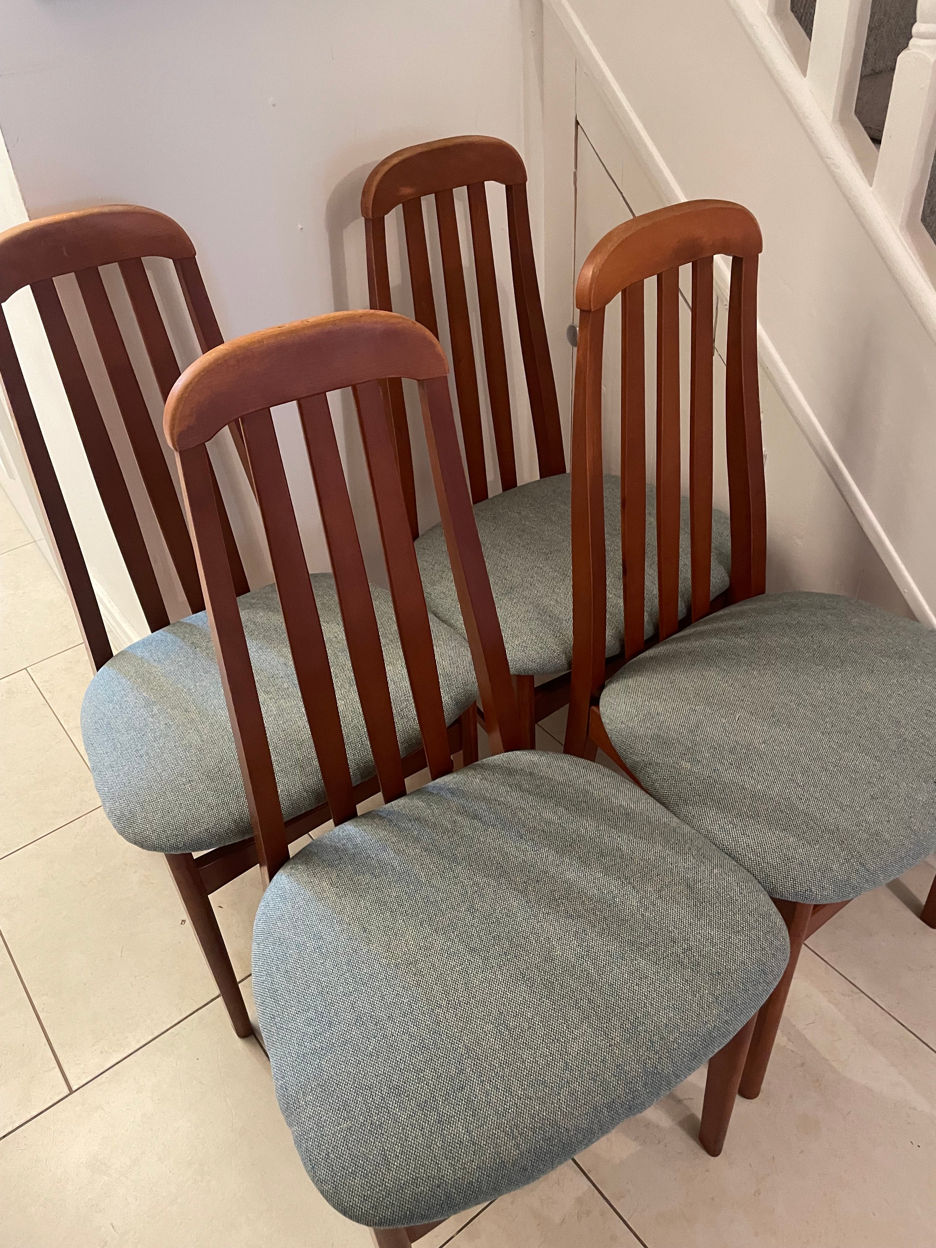 A wooden mid century Jenitique dining chair with a tall slatted backrest and a light blue upholstered seat cushion, shown on a gray wood floor against a white wall by Grace & Joy Furniture