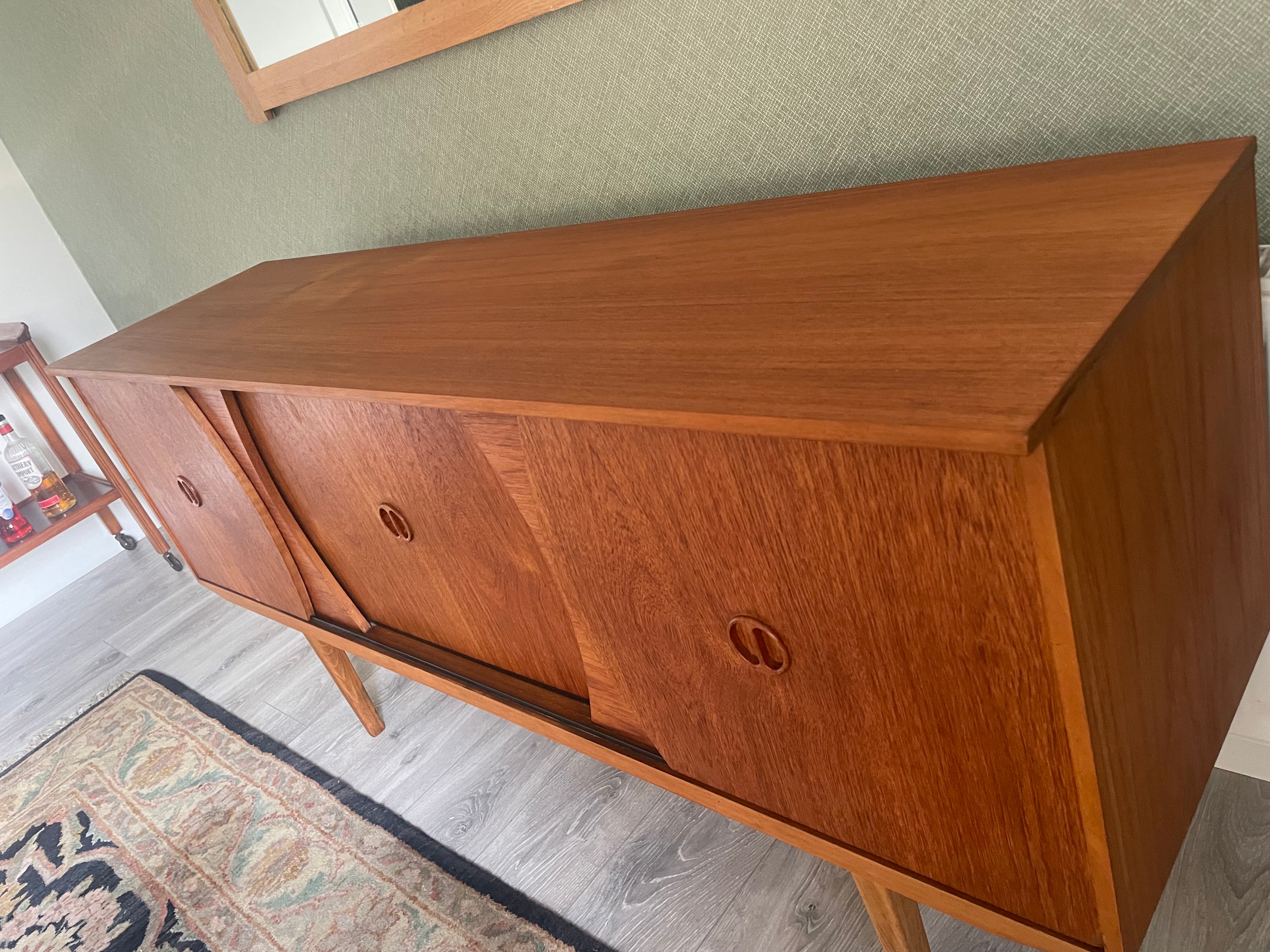 Restored mid-century modern wooden credenza or cabinet with three curved doors and circular pull handles, photographed in a home interior with wood flooring and a patterned rug visible by Grace & Joy Furniture